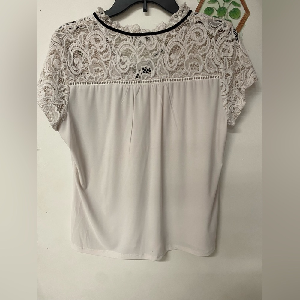 White blouse with black ribbon attached around neck.